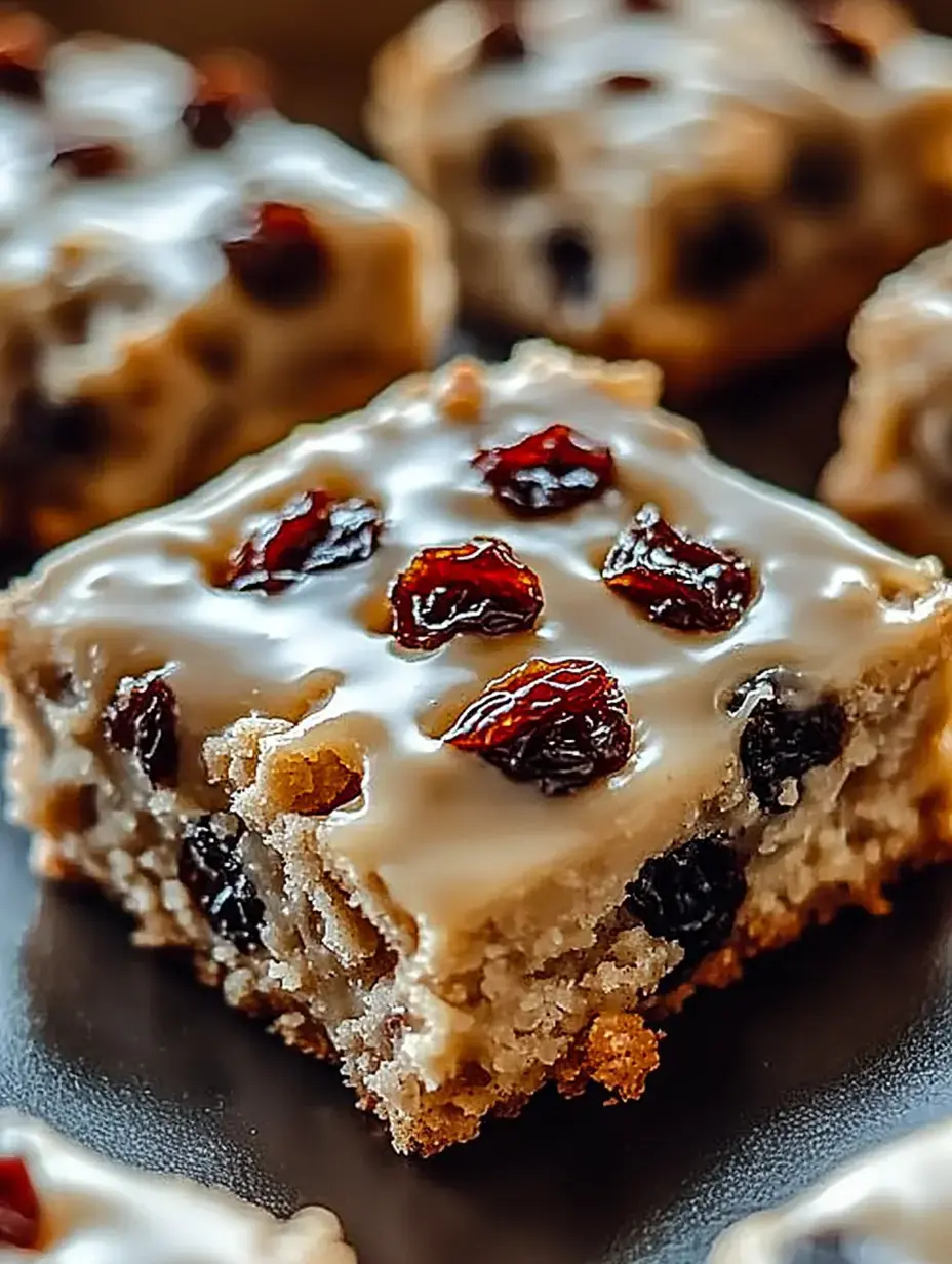 A close-up of a moist dessert square topped with icing and garnished with dried fruits.