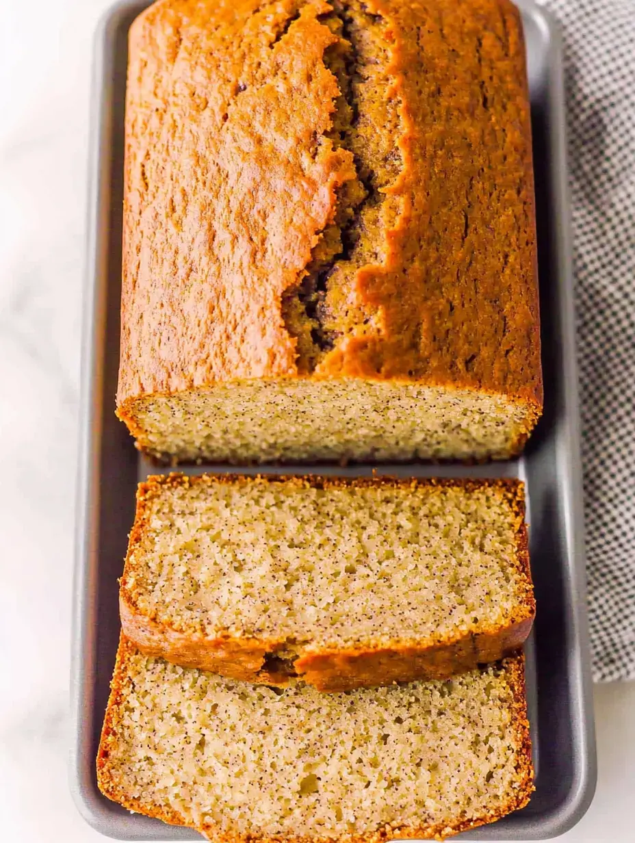 A freshly baked loaf of bread with a cracked top and several slices cut from it, displayed on a gray tray.