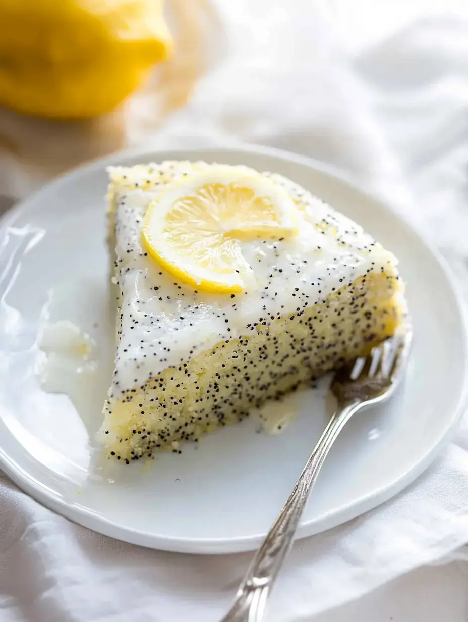 A slice of lemon poppy seed cake topped with a lemon slice and drizzled with icing, served on a white plate alongside a fork.