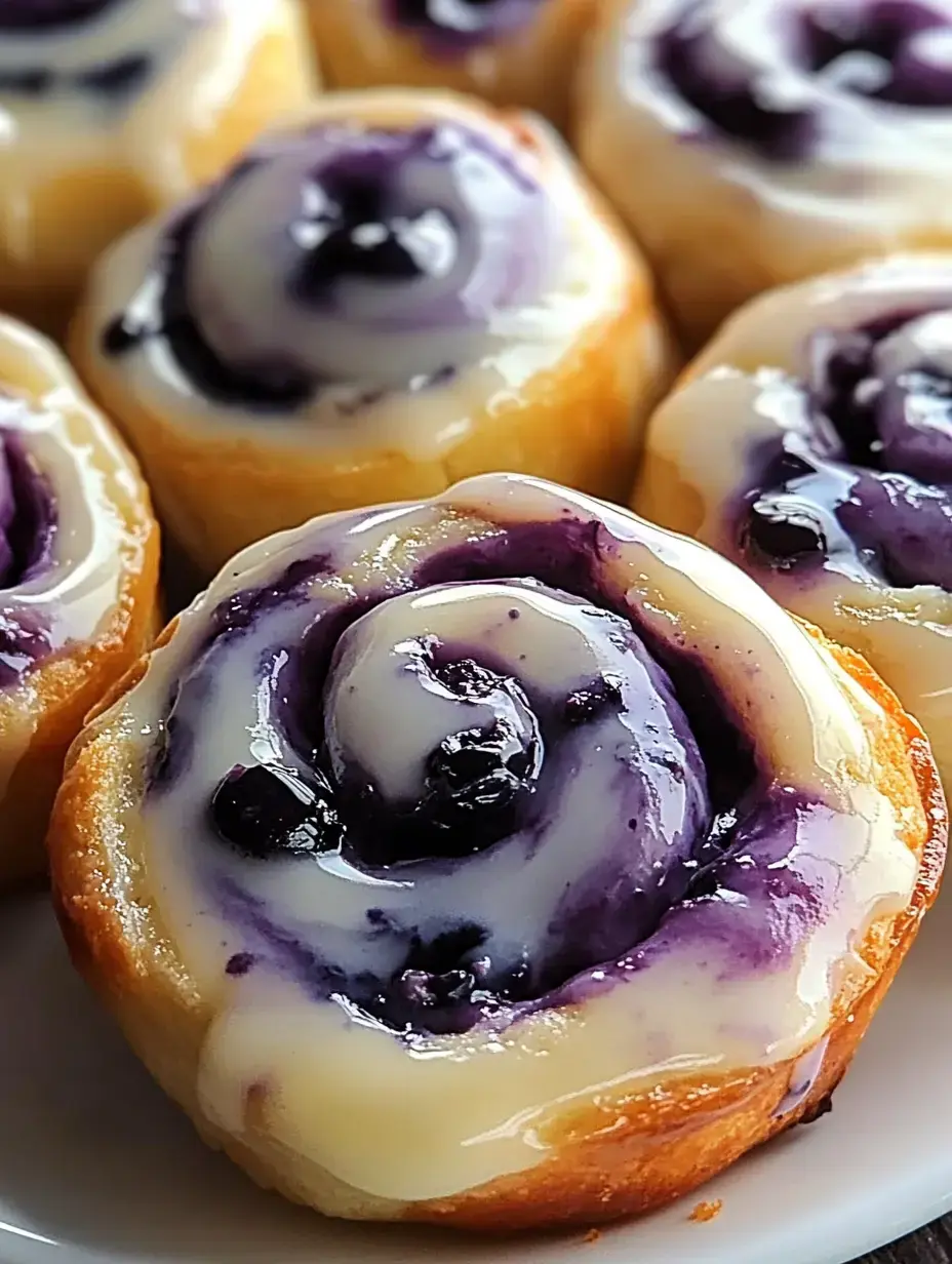 A close-up of delicious cinnamon rolls topped with purple frosting and drizzled with cream cheese icing.