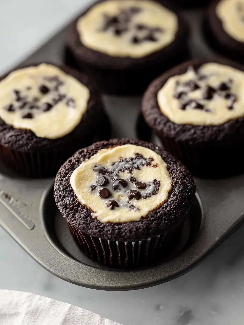 A tray of chocolate cupcakes topped with a creamy layer and sprinkled with chocolate chips.