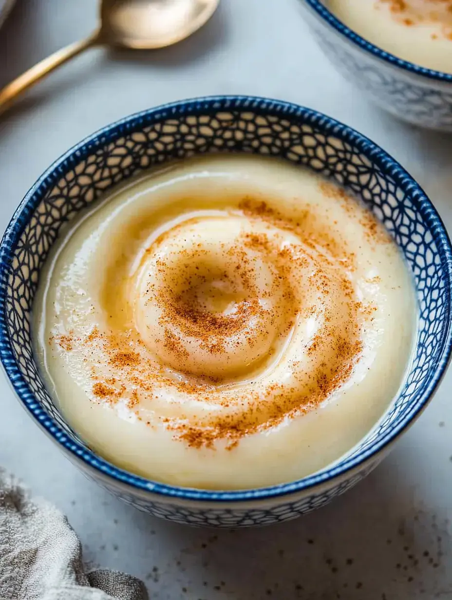 A creamy dessert topped with a swirl of cinnamon in a patterned blue bowl.