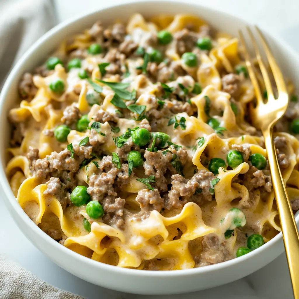 A bowl of pasta with peas and meat.