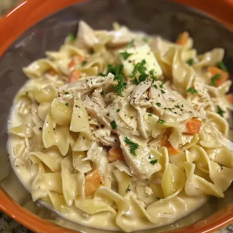 A bowl of pasta with chicken and carrots.