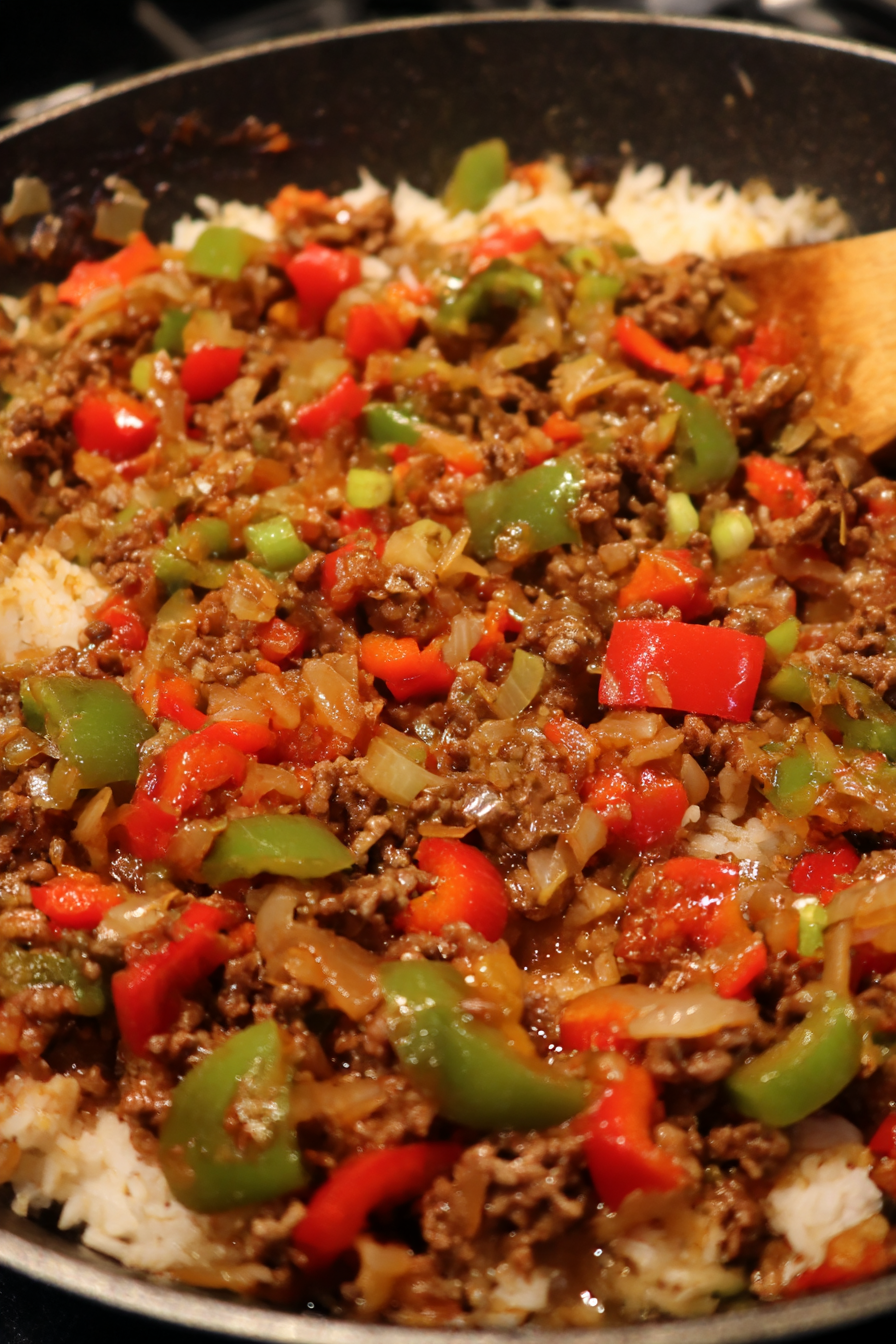 A bowl of food with red peppers and meat.