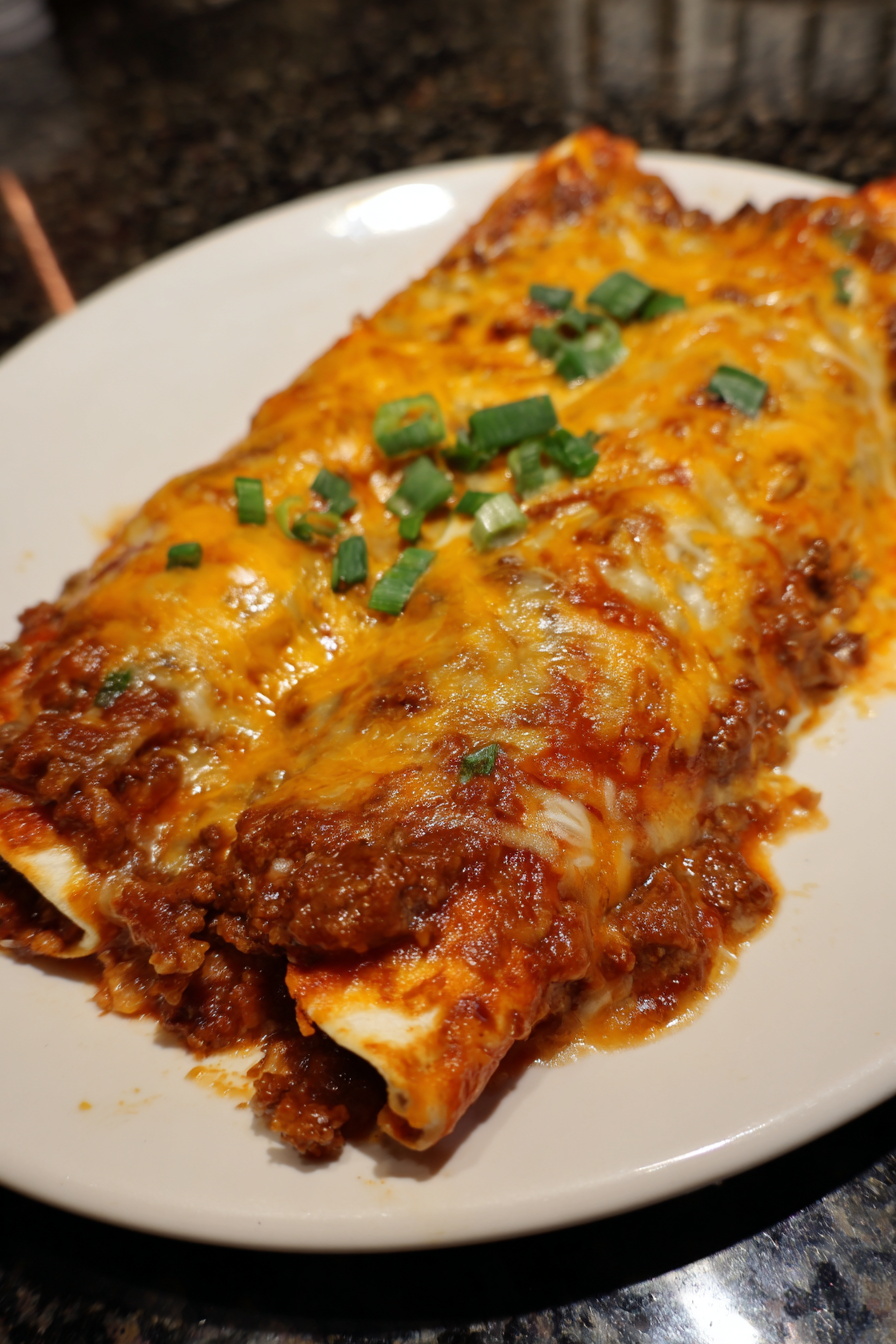 A slice of chicken enchilada on a plate.