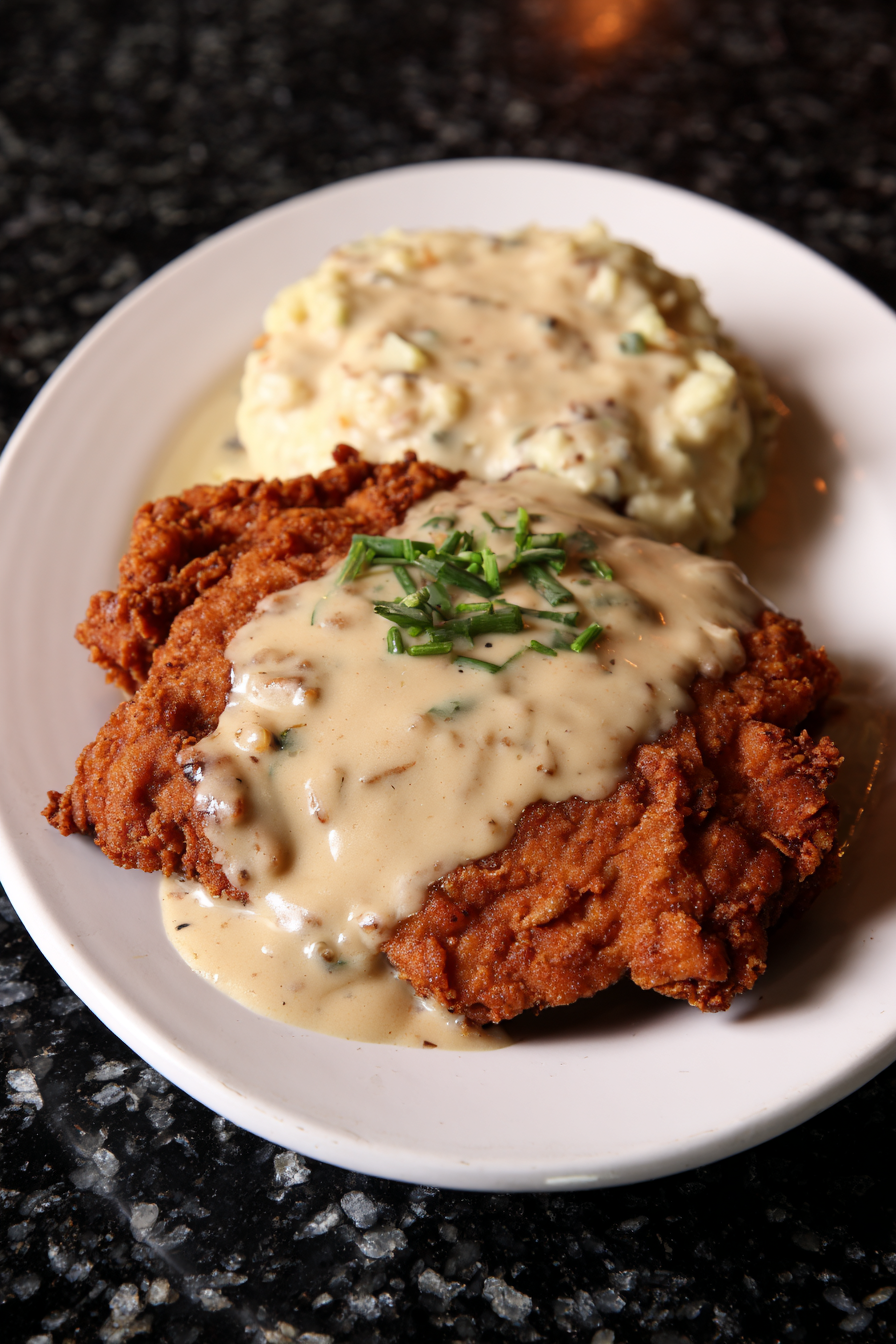 A plate of food with a chicken dish and mashed potatoes.