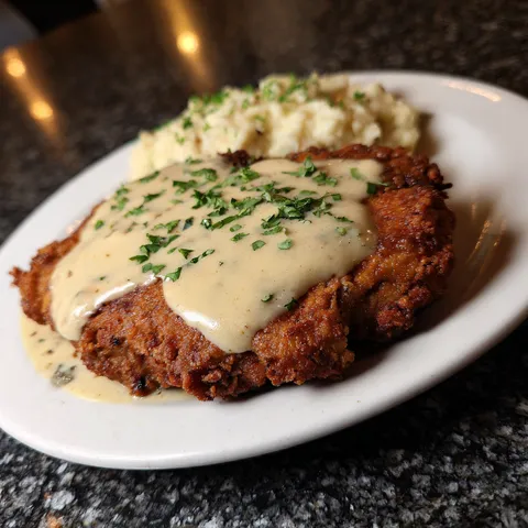 A plate of food with a chicken dish and mashed potatoes.