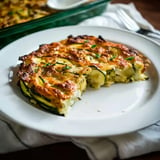 A sliced zucchini dish is served on a plate, showing a golden-brown top and a creamy interior.