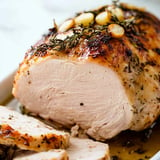 A succulent roasted turkey breast garnished with herbs and thinly sliced on a serving platter.