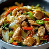 A close-up image of a delicious stir-fried chicken dish with colorful vegetables and a savory sauce.